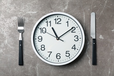 Flat lay composition with clock and utensils on grey background. Time management