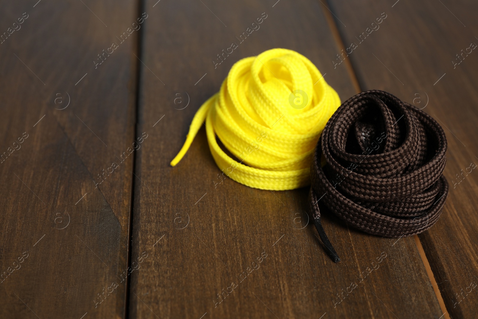 Photo of Yellow and brown shoelaces on wooden background. Space for text