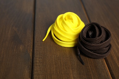 Photo of Yellow and brown shoelaces on wooden background. Space for text