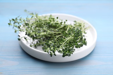 Bunch of aromatic thyme on light blue wooden table, closeup. Fresh herb