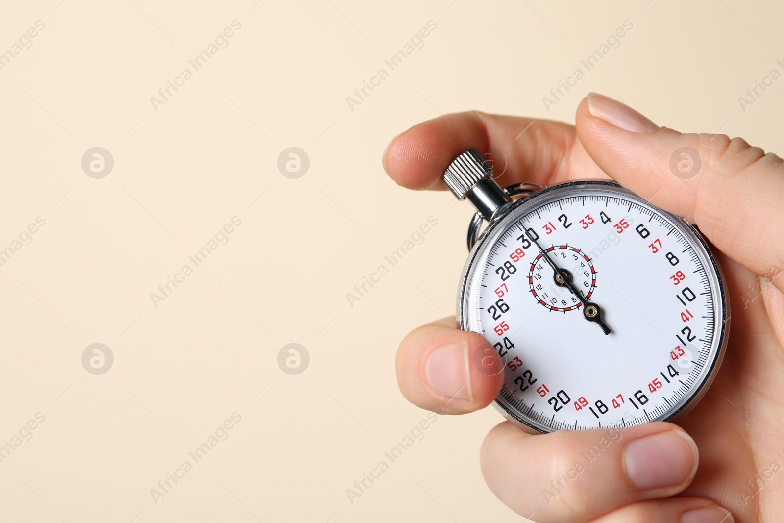 Photo of Woman holding vintage timer on beige background, closeup. Space for text
