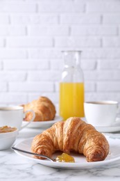 Photo of Tasty breakfast. Fresh croissant and jam on white marble table