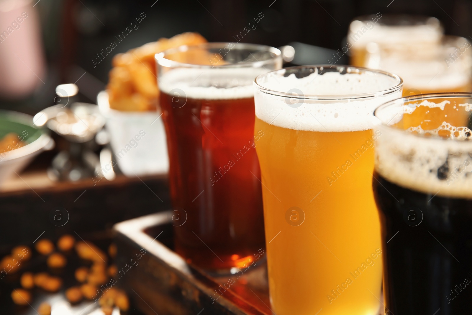 Photo of Glasses of tasty beer on wooden table, closeup