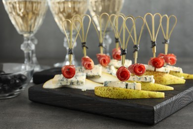 Photo of Tasty canapes with pears, blue cheese and prosciutto on grey table, closeup