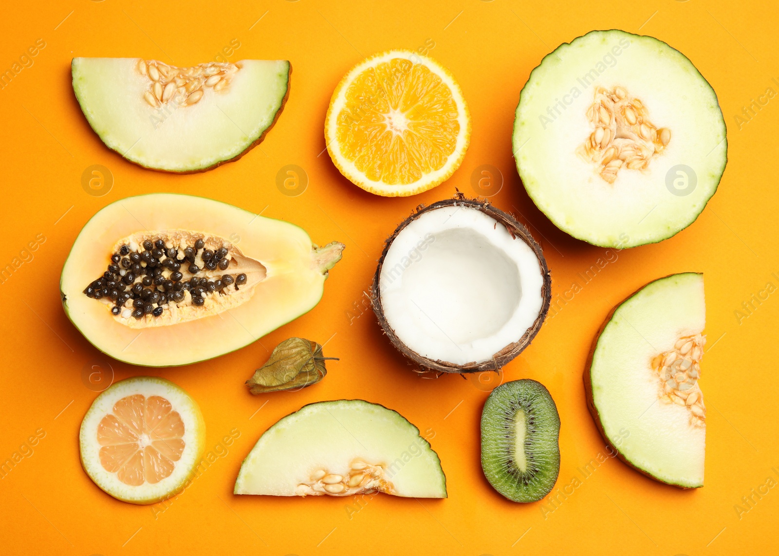 Photo of Flat lay composition with tasty melon and fresh tropical fruits on orange background