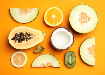 Photo of Flat lay composition with tasty melon and fresh tropical fruits on orange background