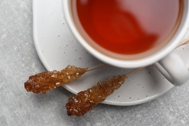 Photo of Sticks with sugar crystals served to tea on grey table, top view