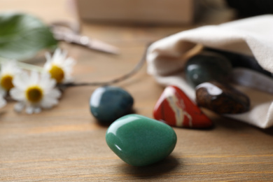 Different healing gemstones on wooden table, closeup