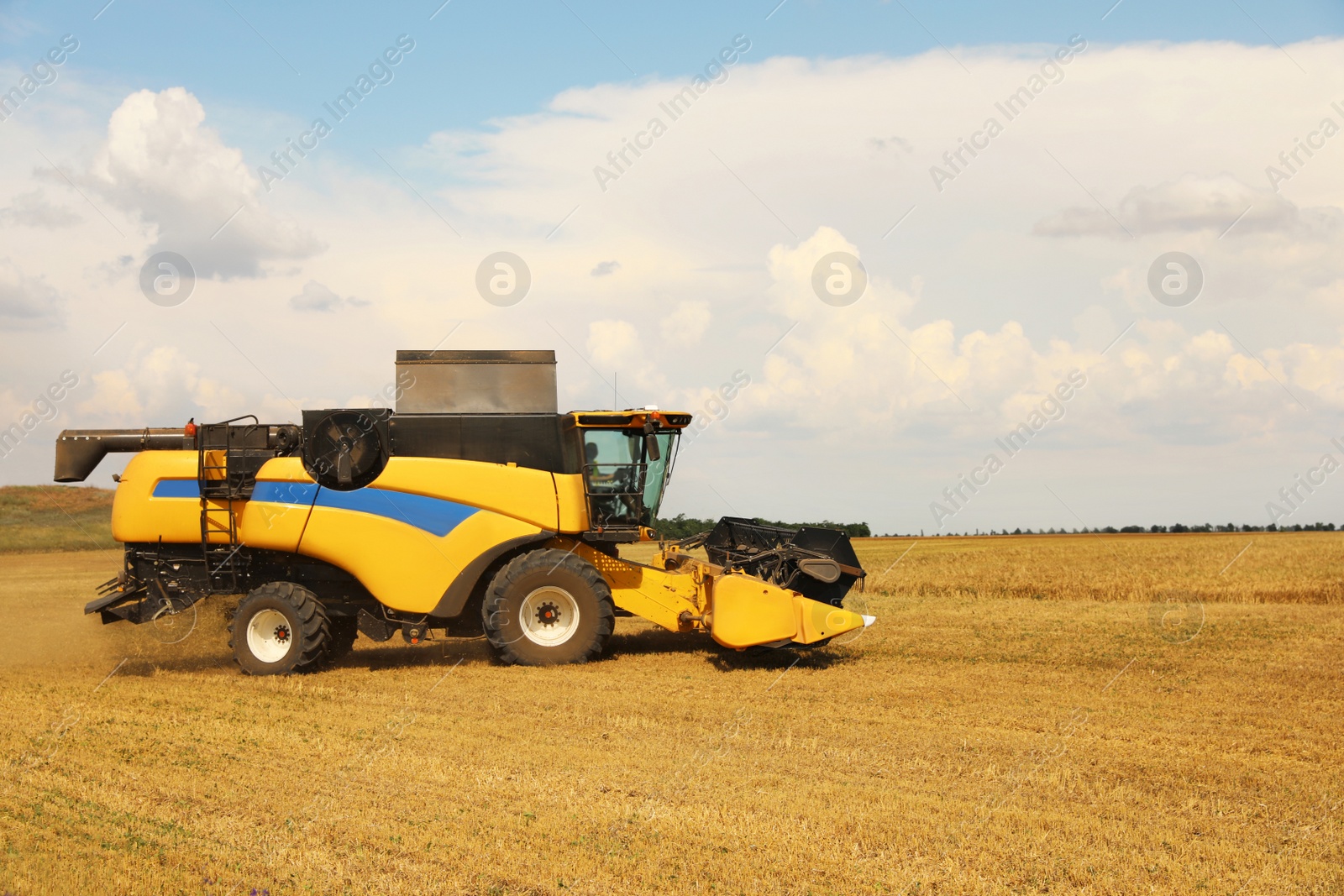 Photo of Modern combine harvester in field on sunny day. Agricultural machinery