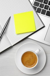 Laptop, notebook with blank sticky note, pen and cup of coffee on white wooden table, flat lay. Space for text