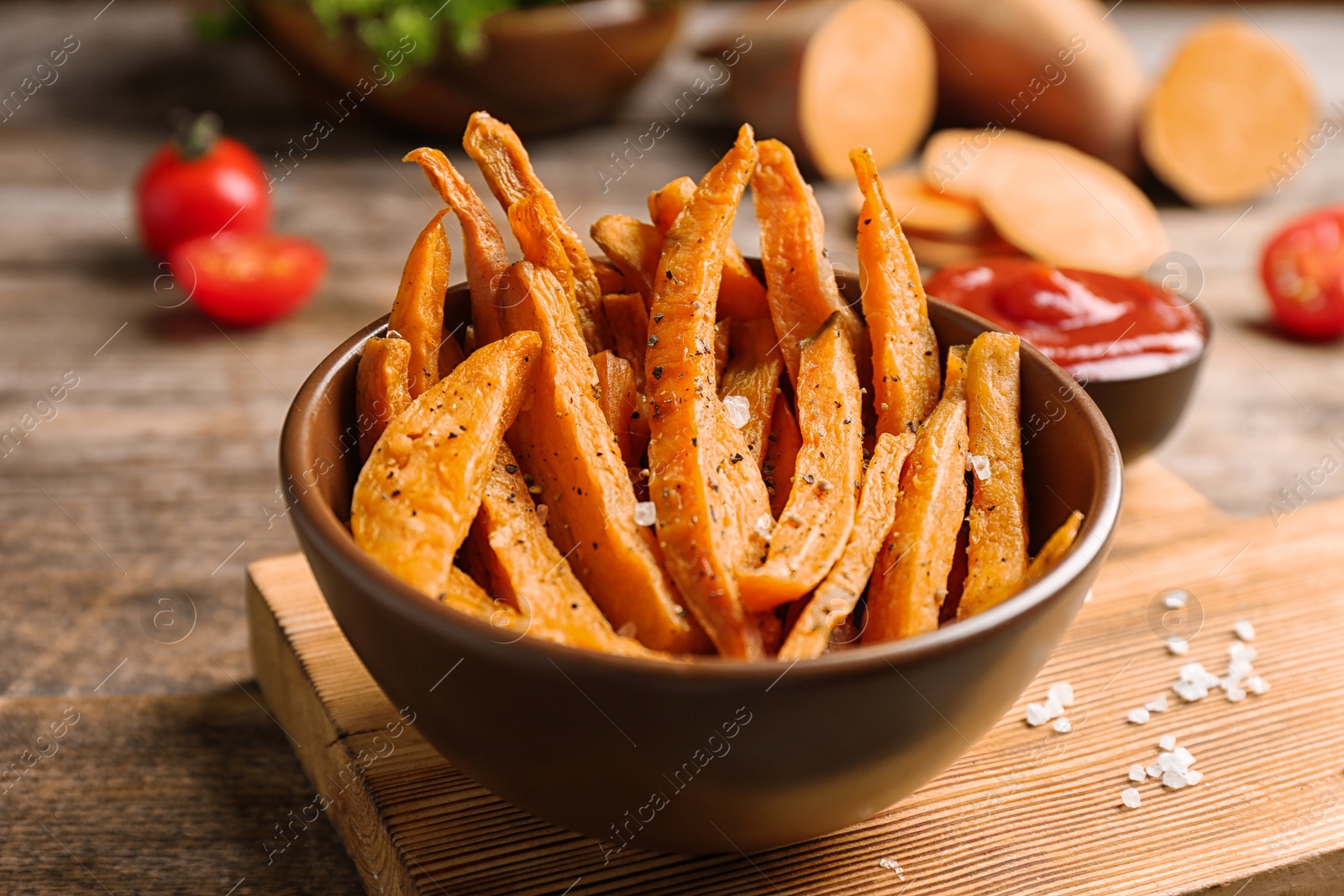 Photo of Bowl with sweet potato fries on wooden table