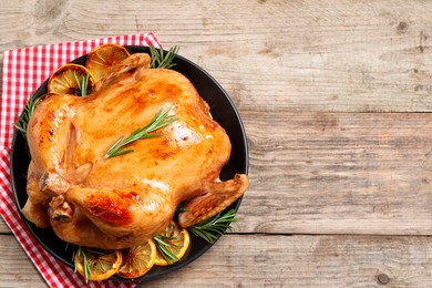 Photo of Tasty roasted chicken with rosemary and lemon on wooden table, top view. Space for text