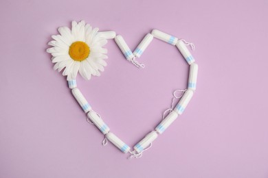 Photo of Tampons and chamomile in shape of heart on lilac background, flat lay. Space for text