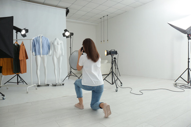 Photo of Professional photographer taking picture of ghost mannequins with modern clothes in photo studio