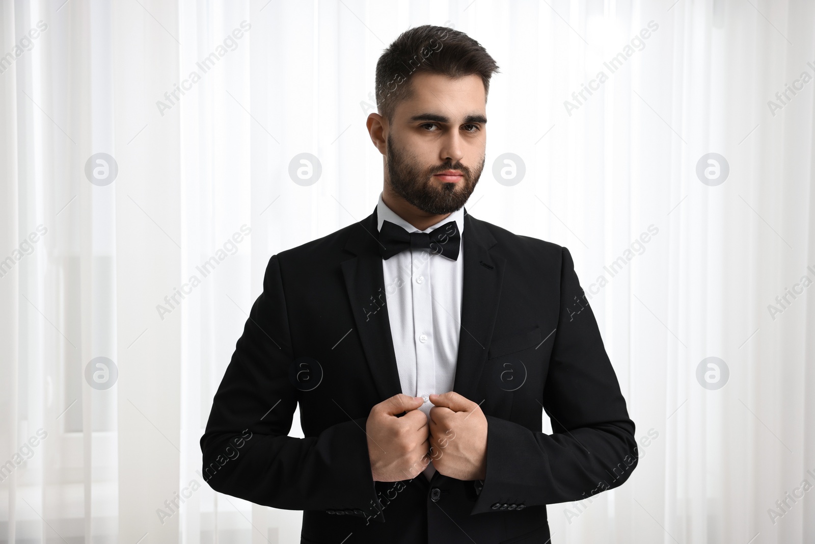 Photo of Portrait of handsome man in suit, shirt and bow tie indoors