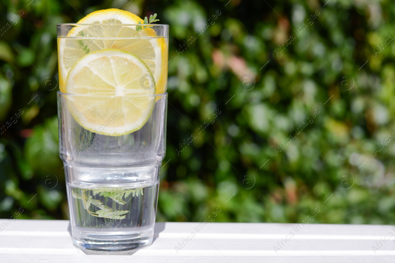 Photo of Delicious refreshing lemonade on white wooden table outdoors, space for text