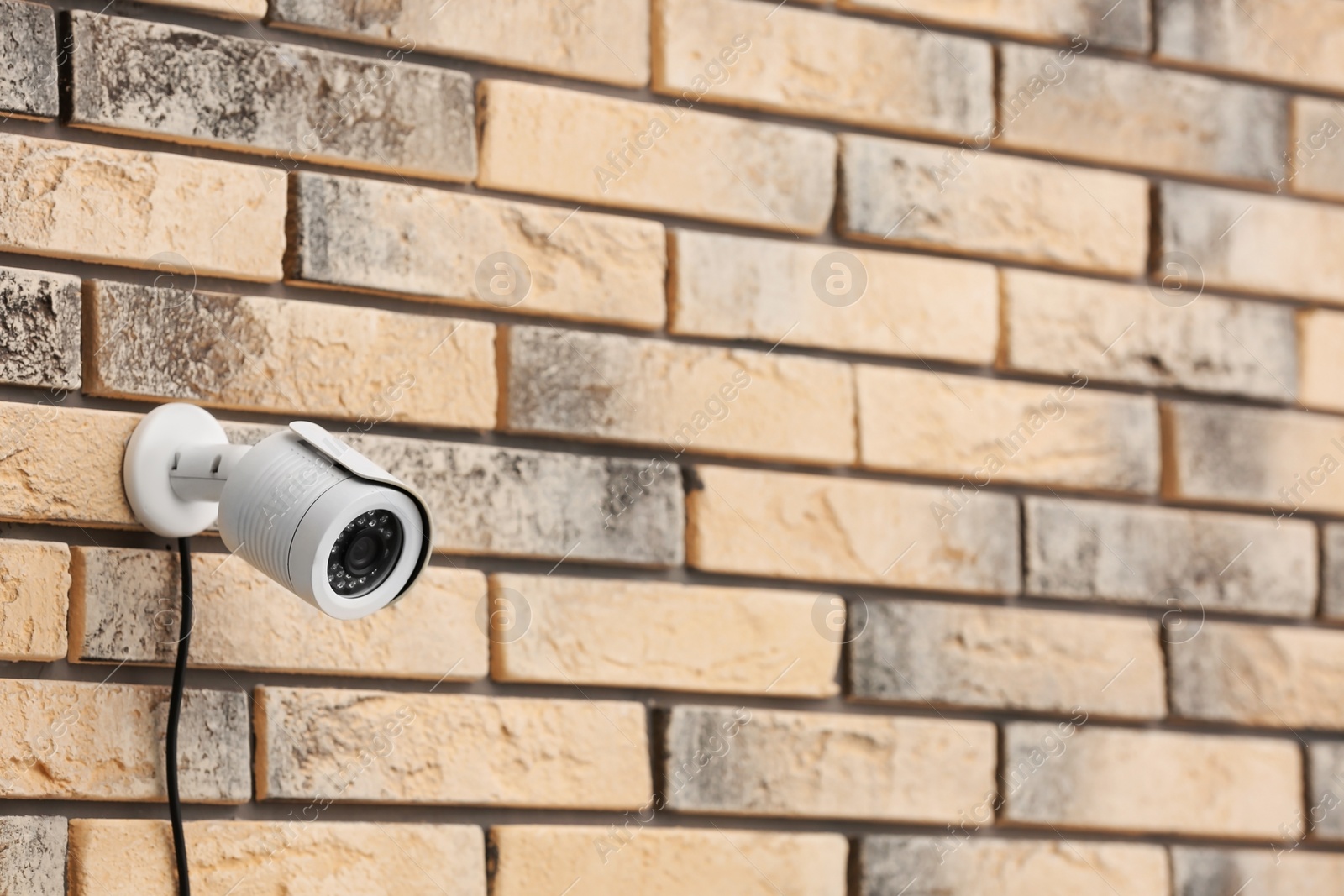 Photo of Modern security CCTV camera on brick wall