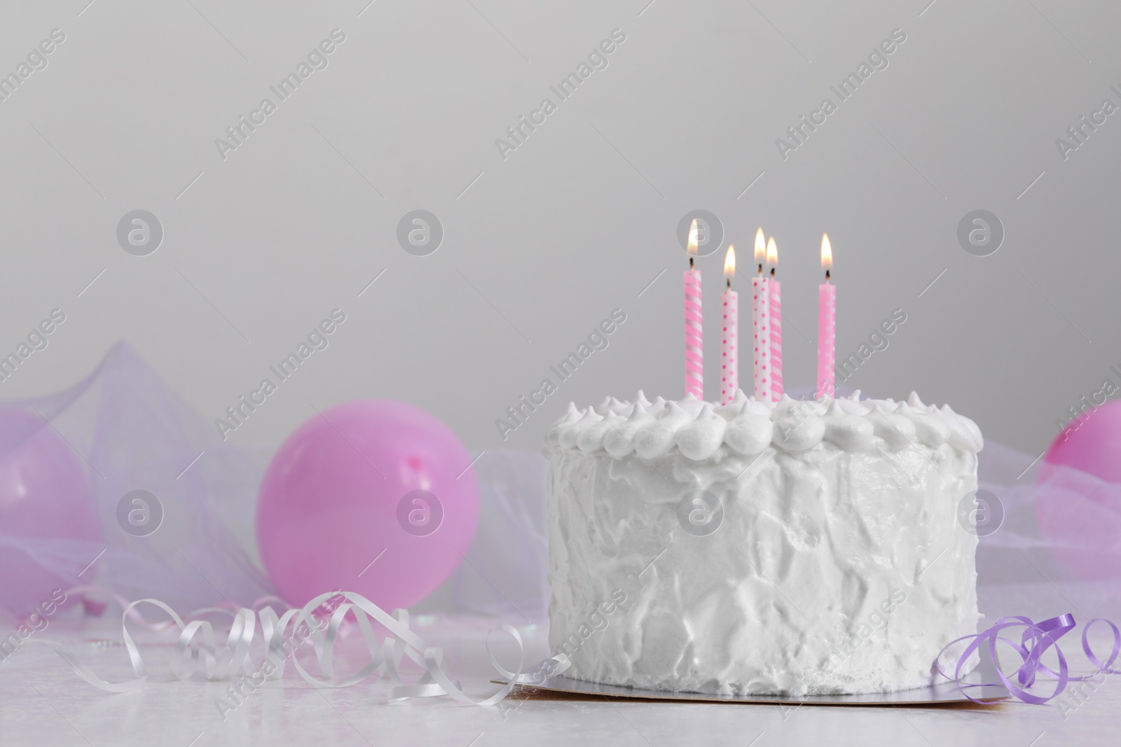 Photo of Delicious cake with burning candles and decorations on white table. Space for text