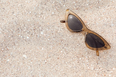 Stylish sunglasses on sandy beach, top view. Space for text