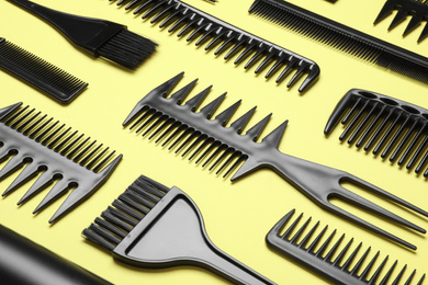Photo of Composition with modern hair combs on yellow background, closeup