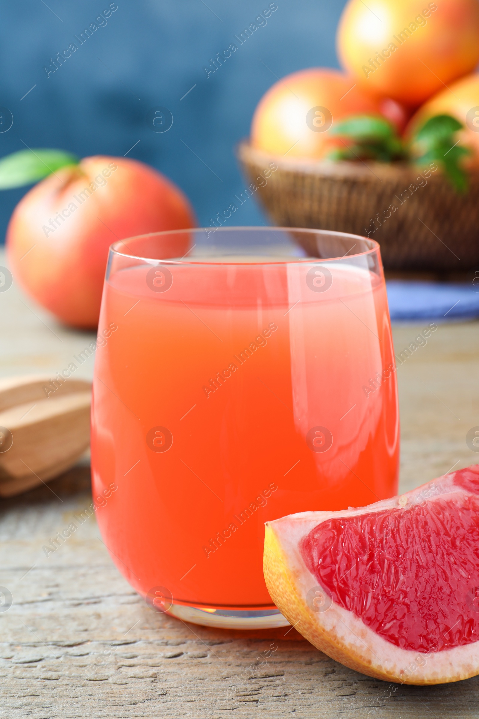 Photo of Tasty freshly made grapefruit juice and fruit on wooden table