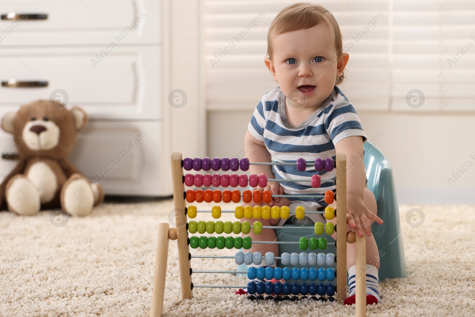 Photo of Little child with abacus sitting on plastic baby potty indoors. Space for text