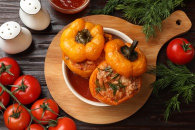 Photo of Tasty stuffed peppers in bowl and products on wooden table, flat lay