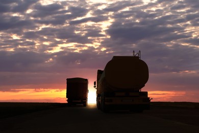 Image of Trucks parked on country road at sunset