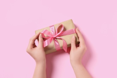 Photo of Woman with gift box on pink background, top view