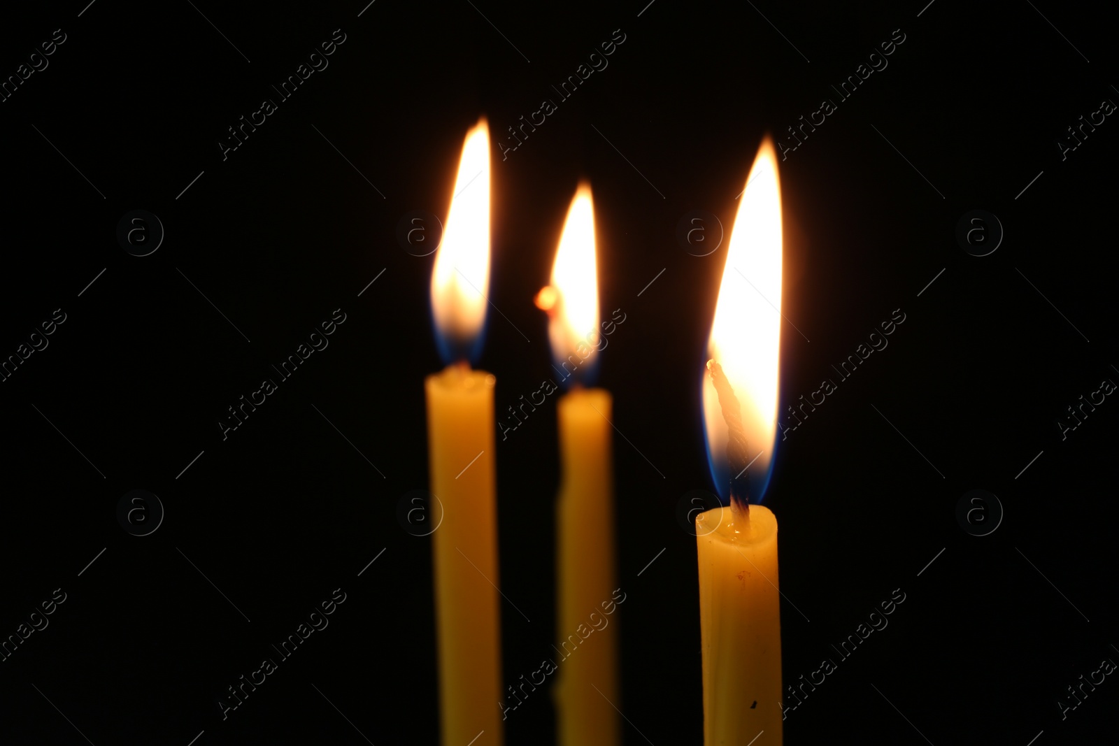 Photo of Burning church candles on dark background, closeup. Space for text