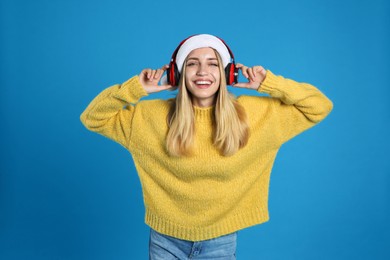 Photo of Happy woman with headphones on blue background. Christmas music