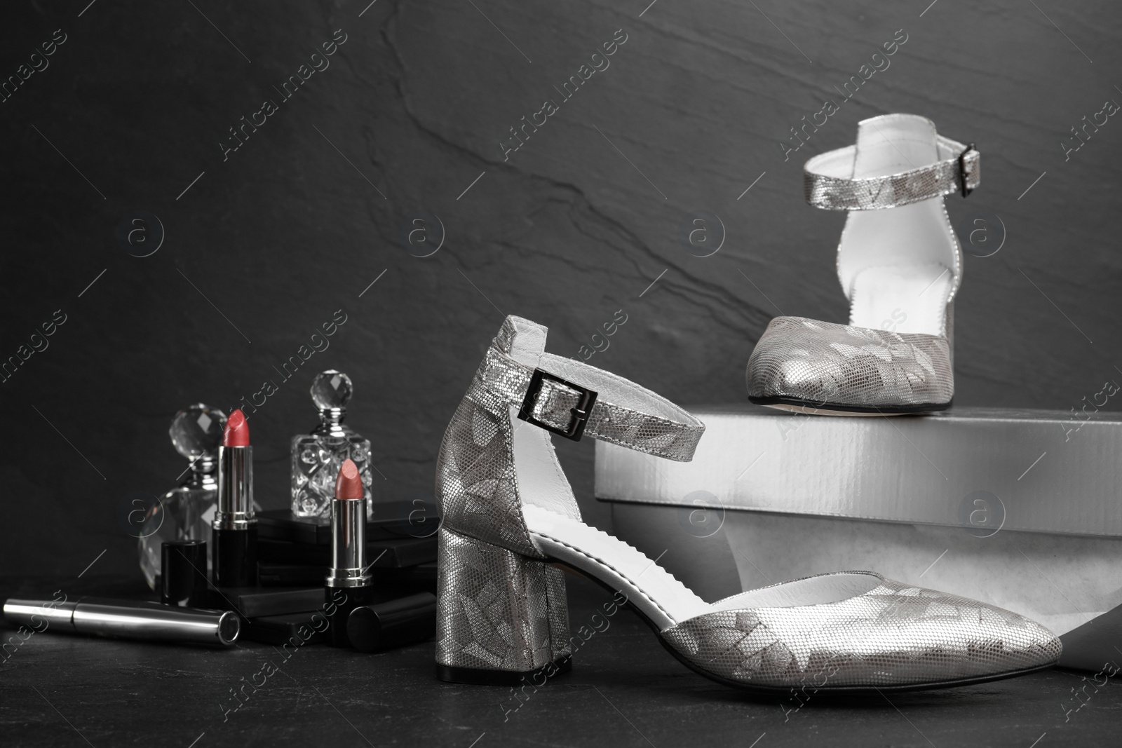 Photo of Composition with stylish silver female shoes on black stone table