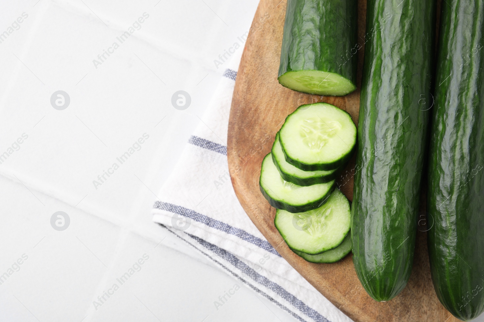 Photo of Fresh cucumbers on white tiled table, top view. Space for text