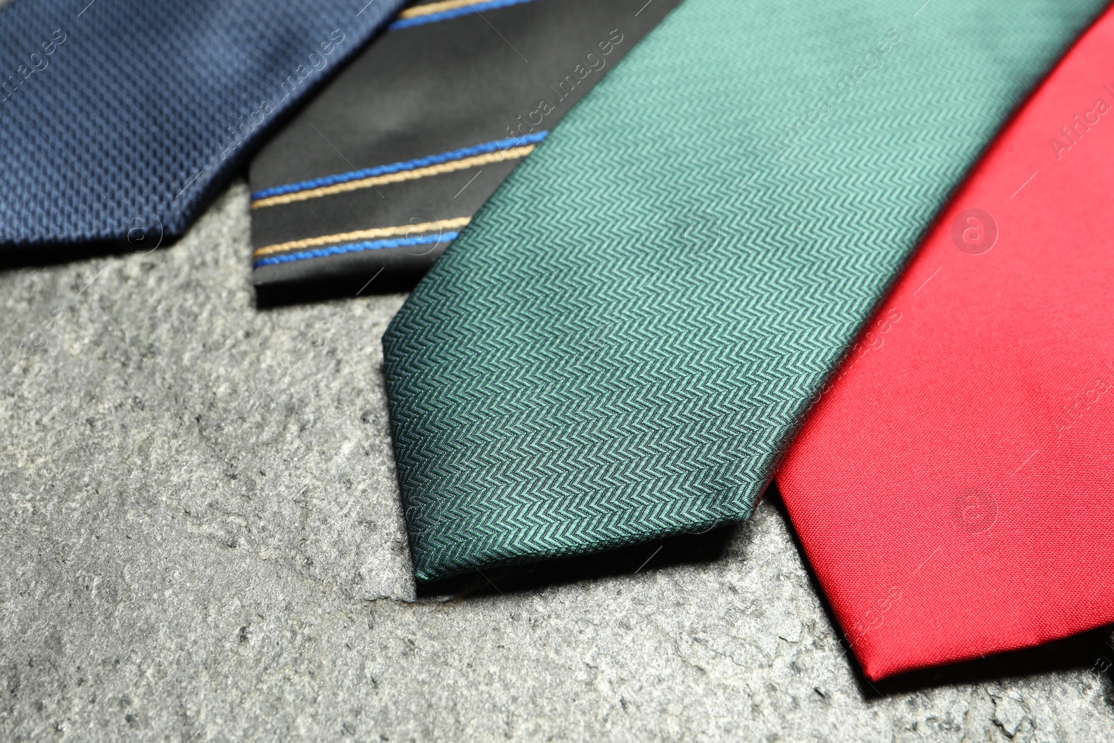 Photo of Different neckties on grey textured background, closeup