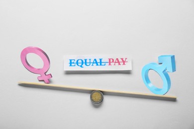 Photo of Equal pay concept. Gender symbols on miniature seesaw against light grey background