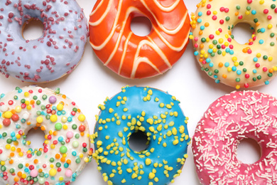 Delicious glazed donuts on white background, flat lay