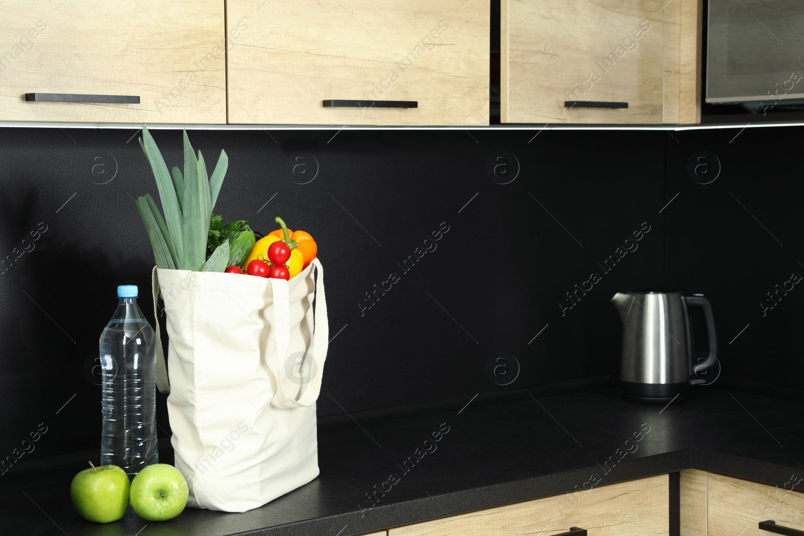 Photo of Tote bag with vegetables and other products on table in kitchen. Space for text