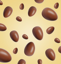 Image of Many chocolate eggs falling on pale light yellow background