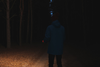Photo of Man with bright flashlight in forest at night