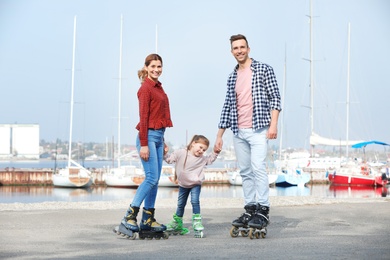 Photo of Happy family roller skating on embankment. Active leisure