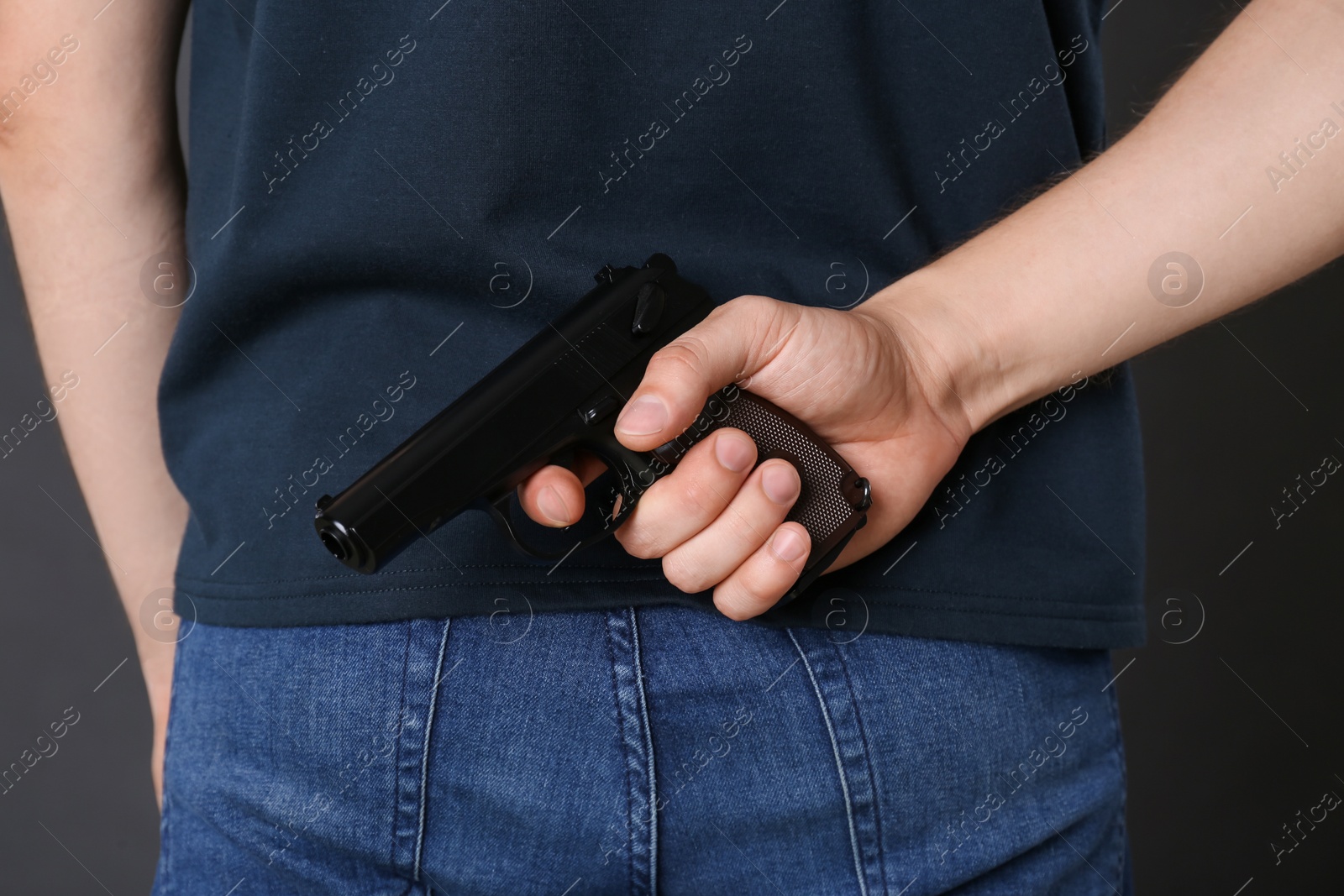 Photo of Man hiding gun behind his back, closeup view