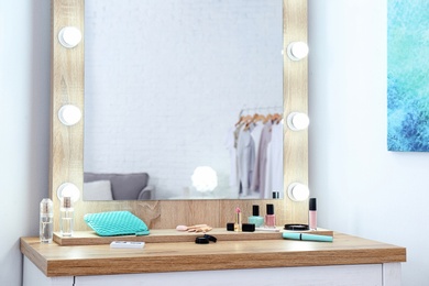 Makeup mirror on table near white wall in dressing room