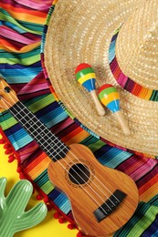Photo of Composition with Mexican sombrero hat, ukulele and maracas on table, top view