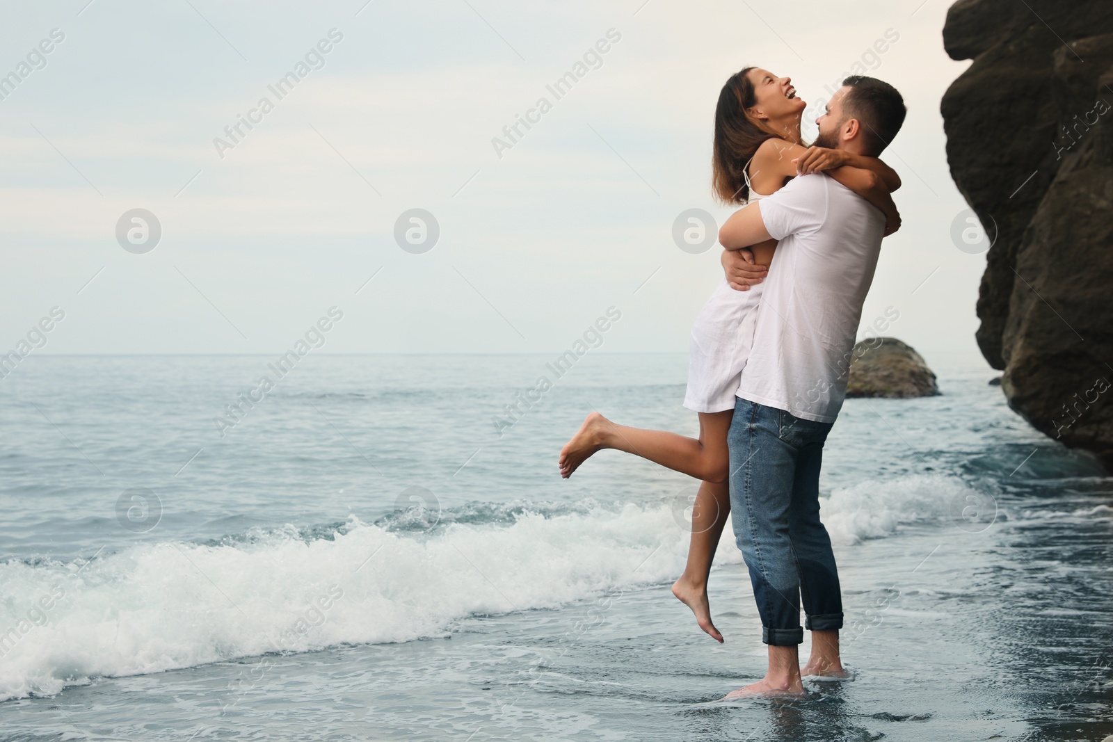 Photo of Happy young couple on beach near sea. Space for text