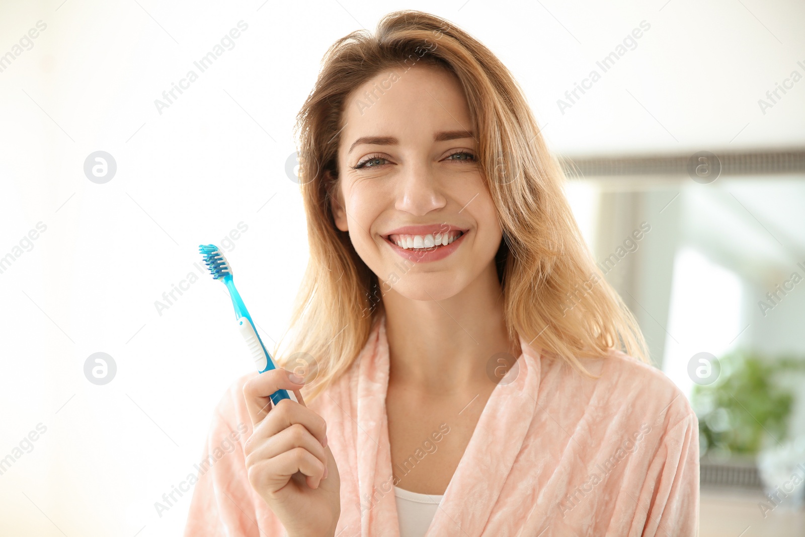 Photo of Portrait of young woman with toothbrush in bathroom. Personal hygiene