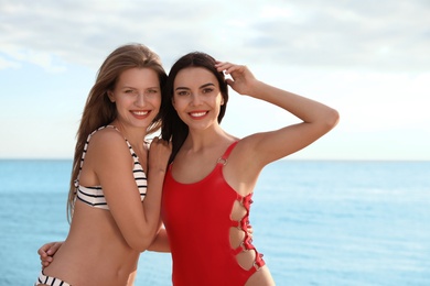 Young woman in bikini with girlfriend on beach. Lovely couple