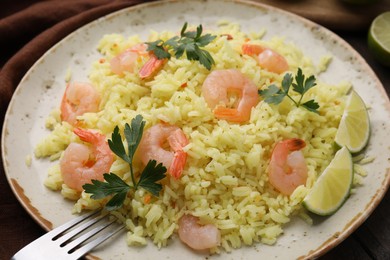 Photo of Delicious risotto with shrimps, lime and parsley on table, closeup