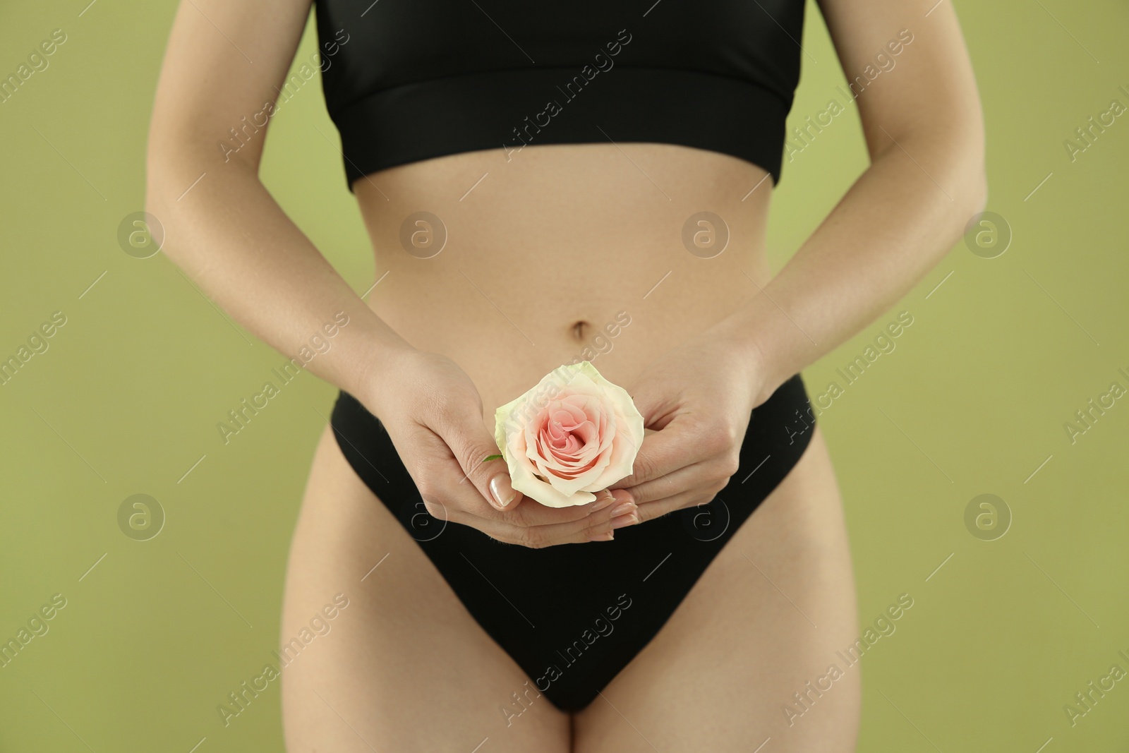 Photo of Gynecology. Woman in underwear with rose flower on green background, closeup