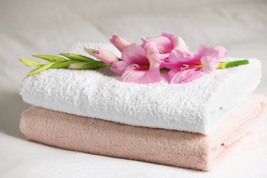 Terry towels with beautiful flower on bed, closeup