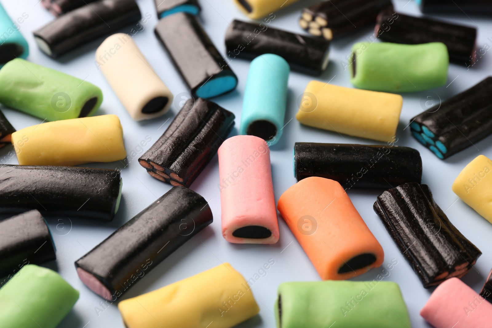 Photo of Many tasty liquorice candies on light blue background, closeup